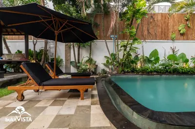 an umbrella and a chair next to a swimming pool at Serayu Mertanadi by Bukit Vista in Seminyak