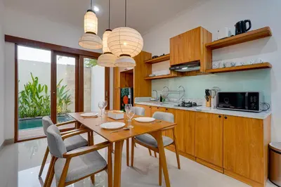 a kitchen with a wooden dining table and chairs at Stylish 3BR Villa Palm Haven 11 near Central Seminyak in Seminyak