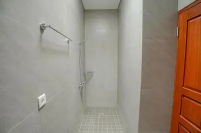 a bathroom with a shower with a glass door at Abimanyu Guest House in Seminyak