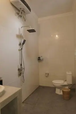 a white bathroom with a toilet and a shower at GB UNLU Villas in Kerobokan