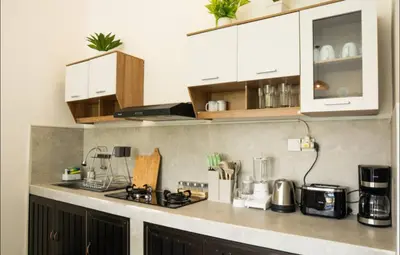 a kitchen with white cabinets and a counter top at GB UNLU Villas in Kerobokan