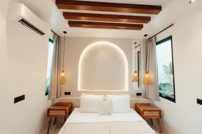 a bedroom with a bed with white sheets and a large window at La Payesa 2 in Canggu