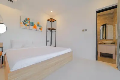 a white bedroom with a bed and a bathroom at 4BR Modern Villa walking dist to Sidewalk Jimbaran in Jimbaran