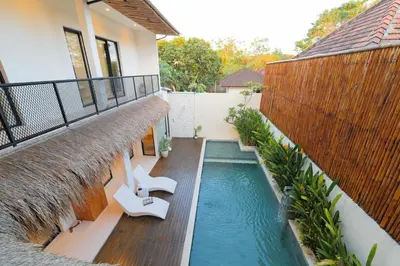 a swimming pool with two chairs and a house at 4BR Modern Villa walking dist to Sidewalk Jimbaran in Jimbaran