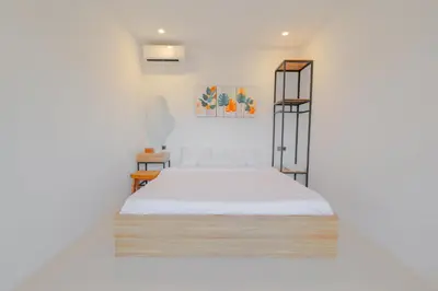 a white room with a bed and a shelf at 4BR Modern Villa walking dist to Sidewalk Jimbaran in Jimbaran