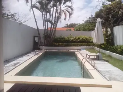a small swimming pool with an umbrella and a table at Villa Private In Kuta Bali in Kuta