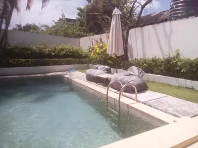 a swimming pool with an umbrella next to a swimming pool at Villa Private In Kuta Bali in Kuta