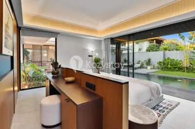 a bedroom with a desk and a bed with a view of a pool at Andra Villa by Kozystay - Natadesa Resort Jimbaran in Jimbaran