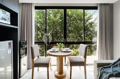 a dining room with a table and chairs and a large window at Caraya by Kozystay - Nusa Dua in Nusa Dua