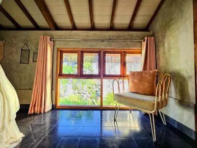 a bedroom with a chair in front of a window at Villa Hibou - New Tropical Luxury 2BR near Canggu in Canggu