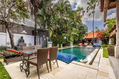 a patio with a table and chairs next to a swimming pool at Seminyak Most Wanted Villa for family vacation in Seminyak
