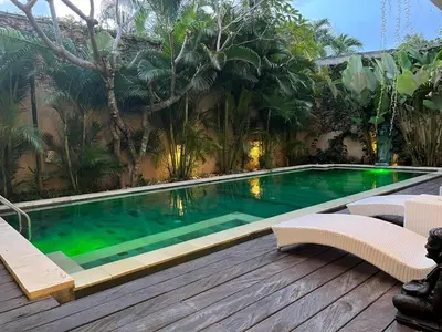 a swimming pool with two chairs and a wooden deck at Villa Josefine, 5 Bedroom pool, rooftop, pool table in Seminyak