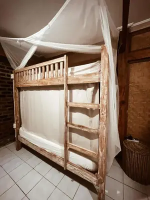 a wooden bunk bed with a white canopy at Da Housetel Kuta in Kuta