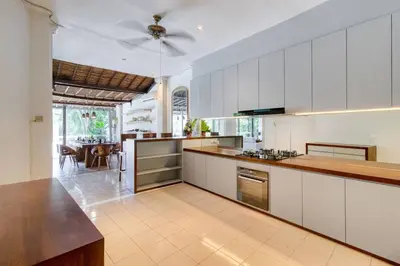 a kitchen with white cabinets and a dining room at 3BR Seminyak Oasis, Sleeps 6, Walk to RestBars in Seminyak