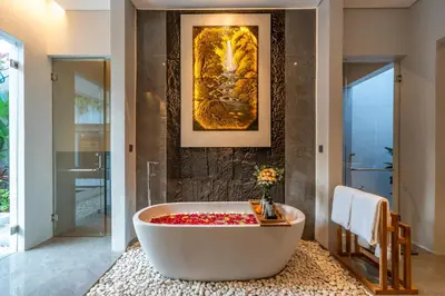 a bath tub in a bathroom with a painting at Villa Narda Seminyak by Nagisa Bali in Legian