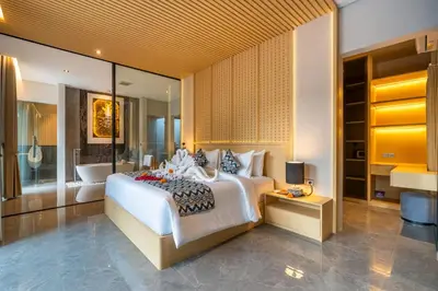 a bedroom with a large white bed and a bathroom at Villa Narda Seminyak by Nagisa Bali in Legian