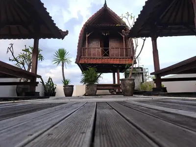 a wooden deck with a building with a balcony at Karmani Villa Managed by Alyssa Villa Management in Ujung