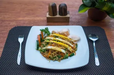 a white plate with a sandwich and vegetables on a table at Deluxe room near seminyak beach in Seminyak