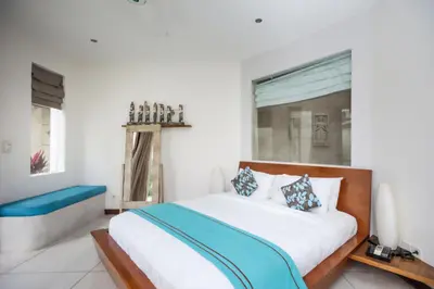 a bedroom with a large white bed with blue accents at Villa K Seminyak by Premier Hospitality Asia in Seminyak