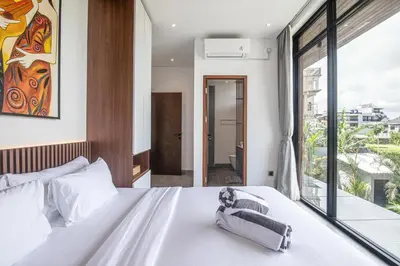 a bedroom with a white bed and a large window at Stunning 5BR Canggu Villa 400m from the Beach in Canggu