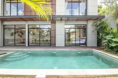 a house with a swimming pool in front of it at Luxury 5-Bedroom Oasis 400 m to Canggu Sand in Canggu