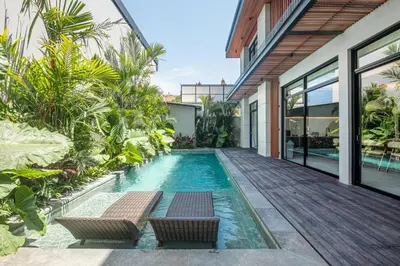 an infinity pool with two chairs and a house at Serene 5-Bedroom Villa 400 m from Batu Bolong in Canggu