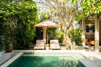 two chairs and an umbrella next to a swimming pool at Anam Khaya - Brand New Villa, Walk to Seminyak Beach in Seminyak