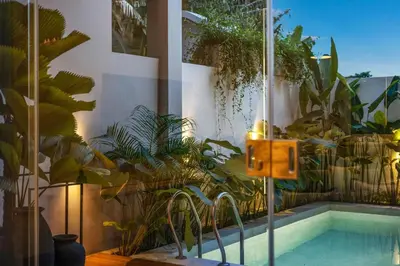 a swimming pool with a bunch of plants next to a building at Modern 2BR Design Haven with green views, rooftop in Kerobokan