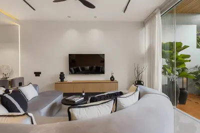a living room with a couch and a tv at Modern 2BR Design Haven with green views, rooftop in Kerobokan
