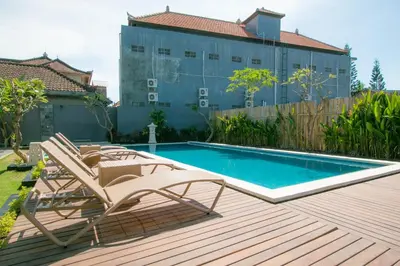 a swimming pool with two lounge chairs next to a building at Srikandi Inn in Jimbaran