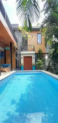 a swimming pool in front of a house at Casa Green Kori in Kerobokan
