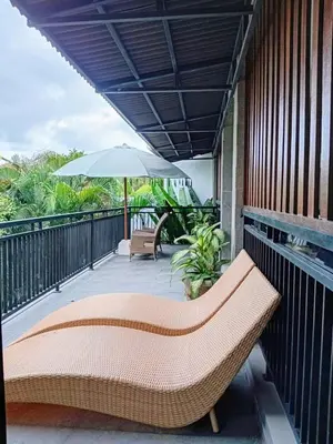 a porch with a bench and an umbrella at Casa Green Kori in Kerobokan
