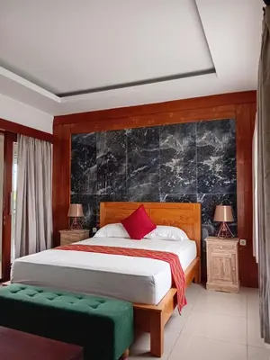 a bedroom with a bed and two tables and two lamps at Casa Green Kori in Kerobokan