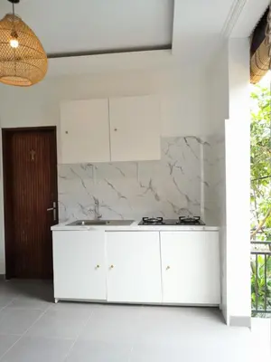 a kitchen with white cabinets and a marble wall at Casa Green Kori in Kerobokan