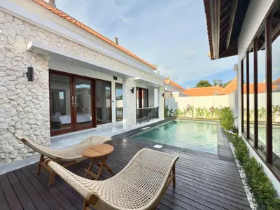 an outdoor deck with chairs and a swimming pool at Chic Villa at Kubu Taullan 3B in Kerobokan