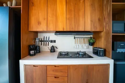 a kitchen with a stove and wooden cabinets at New Luxury 3BR Villa walk to Atlas, Finns & Berawa beach in Canggu