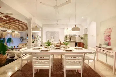a kitchen and dining room with a white table and chairs at Villa Bohème Umalas in Canggu