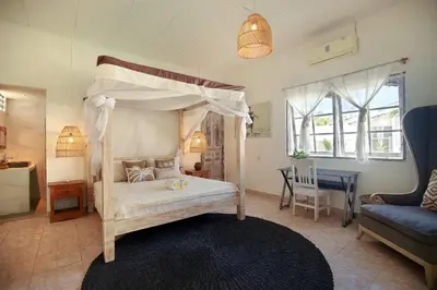 a bedroom with a canopy bed and a living room at Villa Bohème Umalas in Canggu
