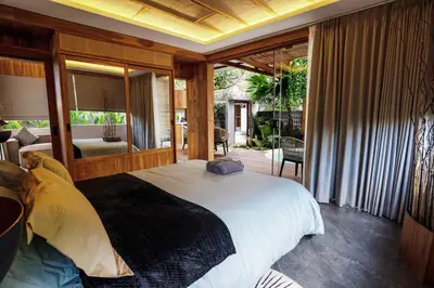 a bedroom with a large bed and a balcony at Kayunida - Charming 1BR Wooden Villa in Seminyak in Seminyak