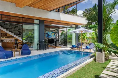 an outdoor pool with blue chairs and a house at Luxury Resort of 4 villas 11 BR Seminyak in Seminyak
