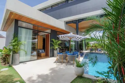 a house with a swimming pool with chairs and an umbrella at Luxury Resort of 4 villas 11 BR Seminyak in Seminyak