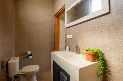 a bathroom with a toilet and a sink with a plant at Casa Ombak in Kerobokan