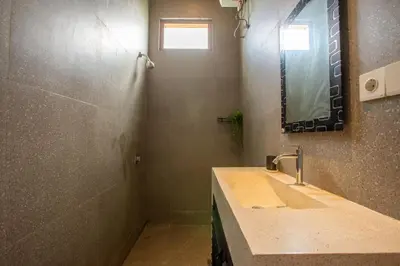 a bathroom with a sink and a shower with a mirror at Casa Ombak in Kerobokan