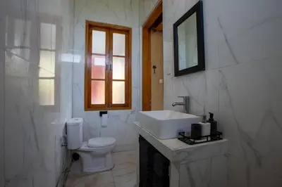 a white bathroom with a sink and a toilet at Casa Ombak in Kerobokan