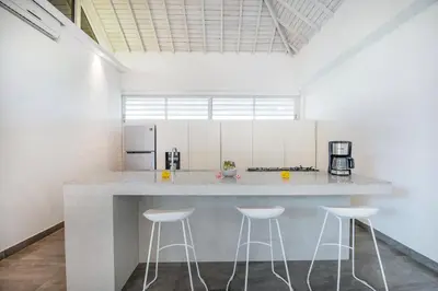 a white kitchen with a counter and stools at Villa Shankara 1 in Canggu