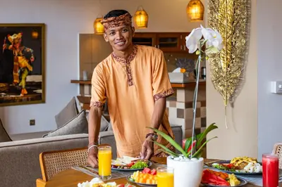 a man standing in front of a table with food at Villa Anvira in Seminyak
