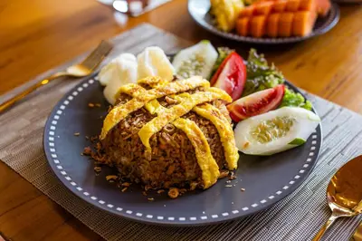 a blue plate with fried food and vegetables on a table at Villa Anvira in Seminyak