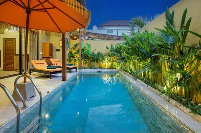 a swimming pool with an umbrella next to a house at Villa Anvira in Seminyak