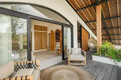 an open patio with a couch and chairs on a porch at Villa Nusa in Canggu