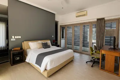 a bedroom with a bed and a desk and a computer at Villa Avrora Batubelig in Canggu